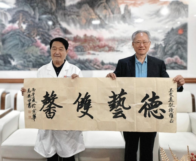 6朝阳军休楹联协会会长马安田向王文远教授赠送自己的书法作品.jpg